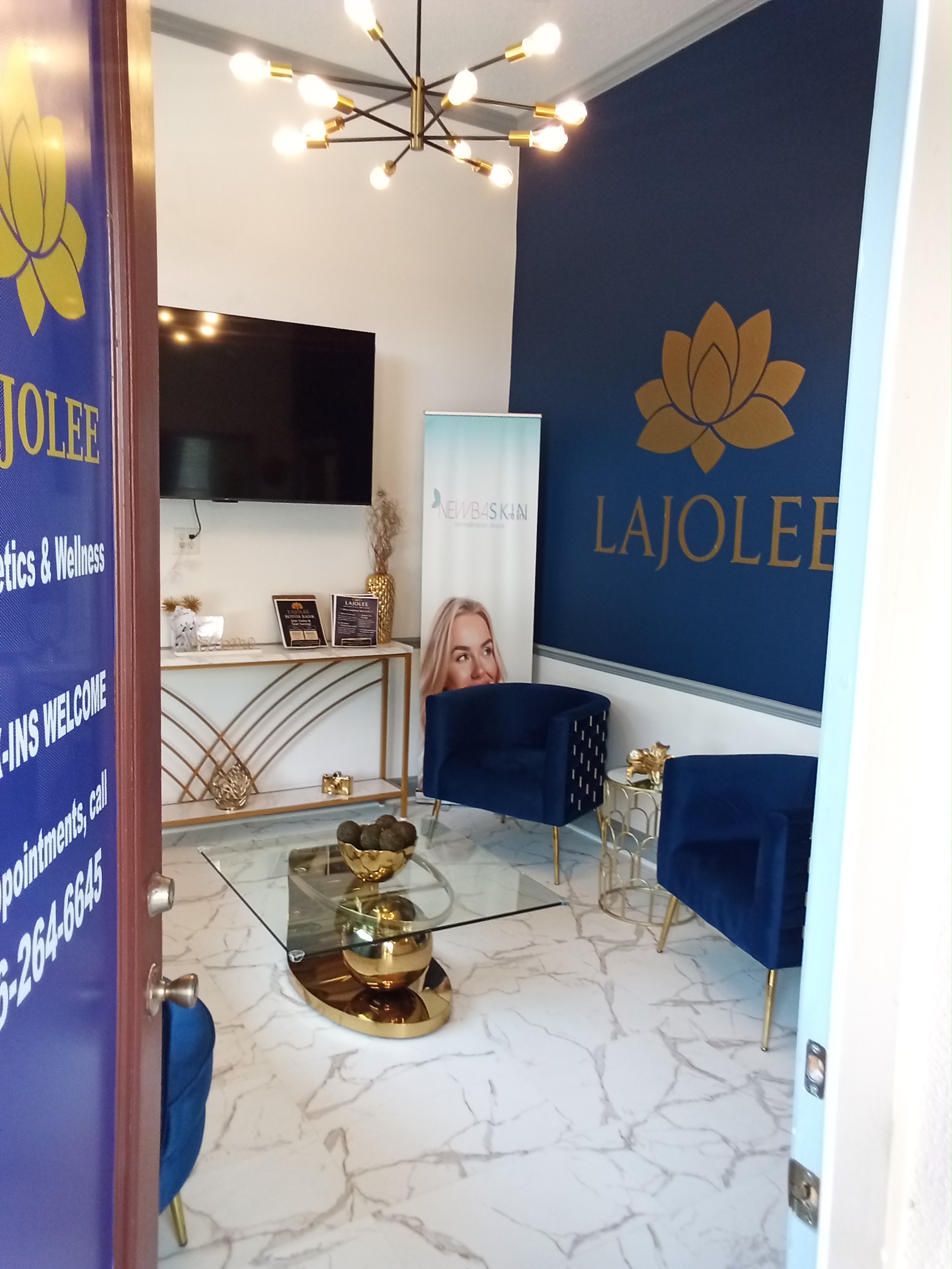 LaJolee Aesthetics & Wellness luxury lobby with navy blue accent wall, gold lotus logo, and velvet seating